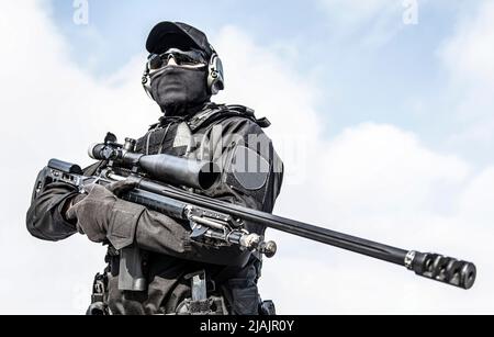 Groupe tactique de police sniper en uniforme noir et masque, tenant fusil de sniper avec oscilloscope optique. Banque D'Images