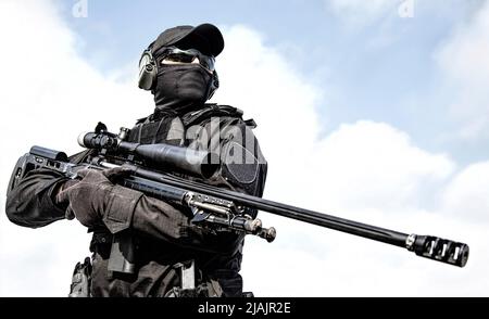 Groupe tactique de police sniper en uniforme noir et masque, tenant fusil de sniper avec oscilloscope optique. Banque D'Images