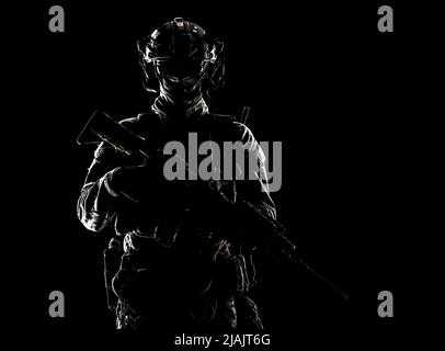 Portrait en studio à clé d'un soldat d'élite des forces spéciales de l'Armée debout avec une carabine d'assaut dans l'obscurité. Banque D'Images