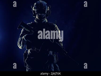Portrait en studio à clé d'un soldat d'élite des forces spéciales de l'Armée debout avec une carabine d'assaut dans l'obscurité. Banque D'Images