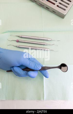 main gantée tenant un miroir dentaire, table de travail avec instruments médicaux pour le traitement, cabinet dentaire, papier peint Banque D'Images