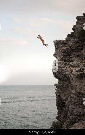 Un homme saute d'une falaise élevée dans la mer Banque D'Images