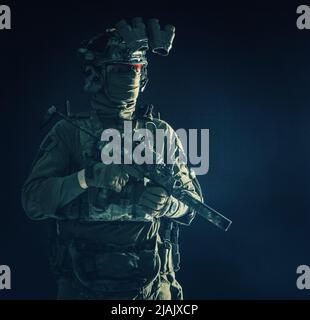 Un combattant commando d'élite debout dans l'obscurité avec un mini-canon de sous-machine et un dispositif de vision nocturne. Banque D'Images