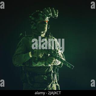 Un combattant commando d'élite debout dans l'obscurité avec un mini-canon de sous-machine et un dispositif de vision nocturne. Banque D'Images