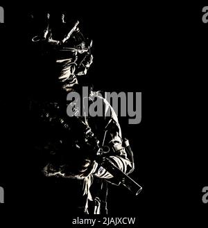 Soldat des forces spéciales équipé d'un dispositif de vision nocturne et d'un canon de sous-machine avec silencieux. Portrait en studio sur fond noir. Banque D'Images