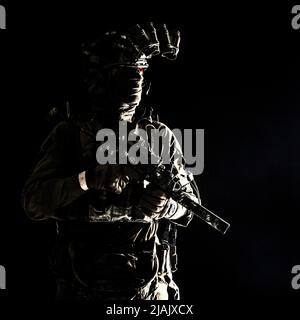 Soldat des forces spéciales équipé d'un dispositif de vision nocturne et d'un canon de sous-machine avec silencieux, en regardant loin. Banque D'Images