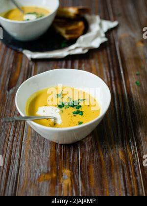 Soupe de courge au noyer cendré sur une table en bois avec serviettes en lin et une agréable ambiance automnale. Banque D'Images