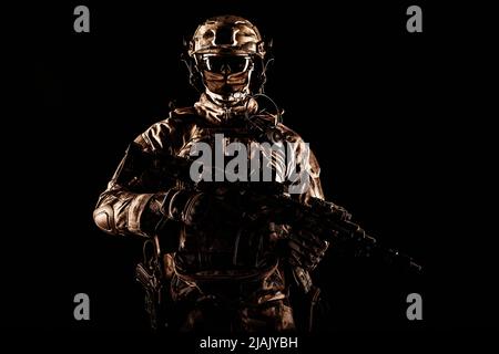 Les opérations spéciales militaire portent un masque, armé d'un canon de sous-machine, sur fond noir. Banque D'Images