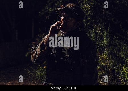 Un soldat de l'armée fume la cigarette la nuit. Banque D'Images