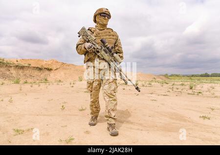 Soldat entièrement équipé et armé avec fusil dans le désert. Banque D'Images