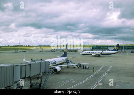 Les personnes qui embarque dans un avion Ryanair à l'aéroport de Londres Stansted tarmac pendant qu'un autre avion roule en taxi Banque D'Images