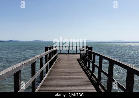 Long quai en bois sur le lac Trasimeno , Italie , dans la côte d'arrière-plan Banque D'Images