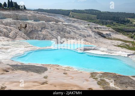 Superbes piscines bleu aqua d'eau de source riche en minéraux naturels avec de nombreuses propriétés de guérison dans la belle Pamukkale, le château de coton de l'ouest de la Turquie, une destination touristique turque majeure. Pamukkale, qui signifie ìcotton castleî en turc, est un site géologique naturel près de Denizli dans le sud-ouest de la Turquie. La région est célèbre pour ses dépôts de minéraux carbonatés laissés par l'eau thermale coulant et est l'une des destinations touristiques les plus populaires en Turquie. Banque D'Images