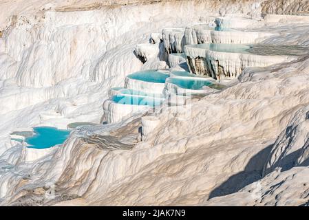 Belles piscines bleu aqua d'eau de source riche en minéraux naturels avec de nombreuses propriétés de guérison dans la belle Pamukkale, le château de coton de l'ouest de la Turquie, une destination touristique turque majeure. Pamukkale, qui signifie ìcotton castleî en turc, est un site géologique naturel près de Denizli dans le sud-ouest de la Turquie. La région est célèbre pour ses dépôts de minéraux carbonatés laissés par l'eau thermale coulant et est l'une des destinations touristiques les plus populaires en Turquie. Banque D'Images