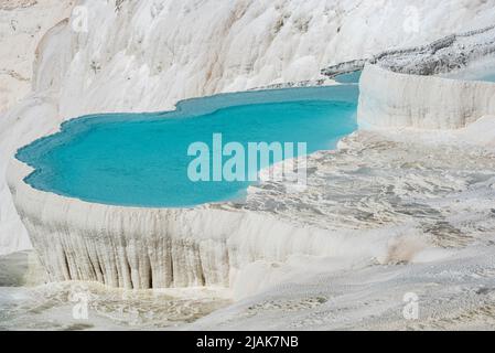 Belles piscines bleu aqua d'eau de source riche en minéraux naturels avec de nombreuses propriétés de guérison dans la belle Pamukkale, le château de coton de l'ouest de la Turquie, une destination touristique turque majeure. Pamukkale, qui signifie ìcotton castleî en turc, est un site géologique naturel près de Denizli dans le sud-ouest de la Turquie. La région est célèbre pour ses dépôts de minéraux carbonatés laissés par l'eau thermale coulant et est l'une des destinations touristiques les plus populaires en Turquie. Banque D'Images