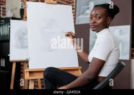 Portrait de l'étudiant peintre souriant et dessin croquis sur toile pendant la classe d'art. Jeune femme profitant de la leçon d'art développer de nouvelles compétences artistiques en studio de créativité. Résolutions du nouvel an Banque D'Images