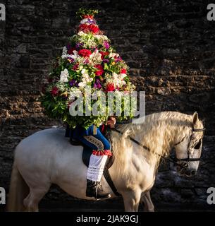 Jon Haddock pose pour une photo tout en portant une grande guirlande pendant le Castleton Garland, une tradition ancienne qui voit le roi cérémonial mener une procession à cheval, tout en portant un cadre fleuri, autour du village de Castleton, dans le Parc national de Peak District, Derbyshire. Date de la photo: Lundi 30 mai 2022. Banque D'Images