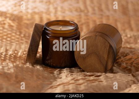 Bougies de soja dans un pot en verre brun avec un couvercle en bois. Aromathérapie. Bougie sur fond beige gros plan. Placer une étiquette. Cire et mèche. Décoration d'intérieur. Fait à la main. Désodorisant. Concept de bougie de soja Banque D'Images