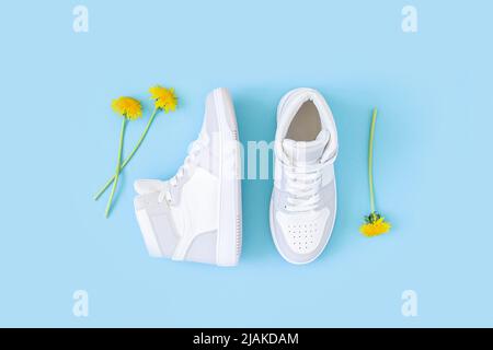 Chaussures de sport, baskets et fleurs jaunes sur fond bleu. Sport activité de loisirs en été concept. Vue de dessus Flat lay. Banque D'Images