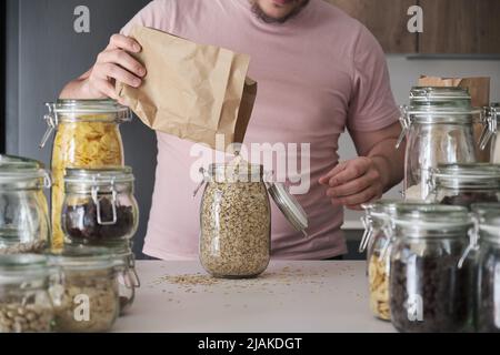 latins méconnaissables remplissant un pot de flocons d'avoine d'un sac en papier. Banque D'Images