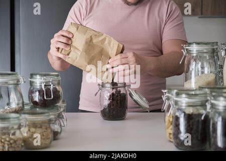 latins méconnaissables remplissant un pot de raisins secs d'un sac en papier. Banque D'Images