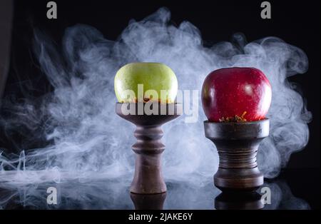 bols à narguilé de fruits avec tabac, deux pommes et fumée sur fond noir Banque D'Images