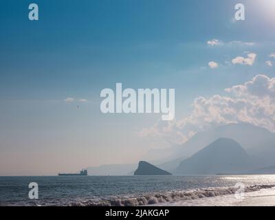 Cargo en bleu méditerranéen calme en Anatalya. Voyage le long de la mer Méditerranée, vue sur la côte rocheuse d'Antalya. Dans la distance, les navires de cargaison sont Banque D'Images