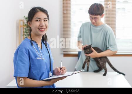 Concept de soins pour animaux de compagnie, le vétérinaire féminin écrit la prescription sur le presse-papiers après examen de santé chat. Banque D'Images