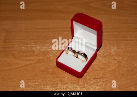 Anneaux de mariage de mariée dans une boîte rouge pour les anneaux de mariage sur une table en bois. Banque D'Images