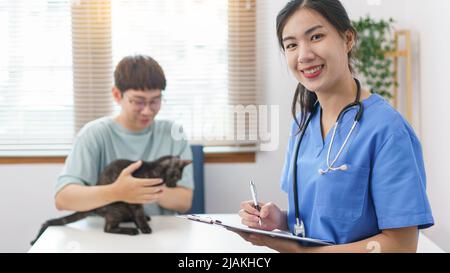 Concept de soins pour animaux de compagnie, le vétérinaire féminin écrit la prescription sur le presse-papiers après examen de santé chat. Banque D'Images