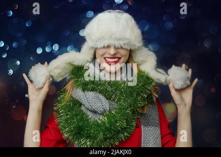 la fille a tiré son chapeau d'hiver sur ses yeux avec un sourire. Banque D'Images