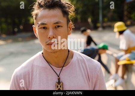 Un garçon asiatique avec des dreadlocks passe du temps avec ses amis au skate Park en plein air Banque D'Images