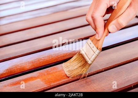 Le vernis protège le bois du jardin des fissures, de la peinture à l'huile de teck. Banque D'Images