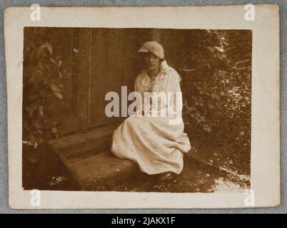 Femme en robe blanche assise sur deux marches menant à la porte de la maison inconnue Banque D'Images