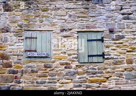 Un vieux mur en pierre récemment repointée contenant deux portes à charnières peintes en bois. Banque D'Images