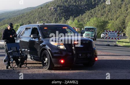 Pecos, États-Unis. 21st mai 2022. Nouveau-Mexique sur 21 mai 2022, des camions d'incendie et du personnel quittent leurs positions stationnées dans le haut du canyon Pecos et se dirigent pour leur changement de quart dans le camp d'incendie voisin situé dans la ville de Pecos. Un officier de la patrouille d'État du Nouveau-Mexique occupe un pâté de maisons pour empêcher tous les combattants sauf les pompiers de monter sur la route du canyon, New Mexico State Highway 63. (Photo de Steve Clevenger/Sipa USA) crédit: SIPA USA/Alay Live News Banque D'Images