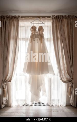 Robe de mariage accrochée à la porte de la chambre d'hôtel. Banque D'Images