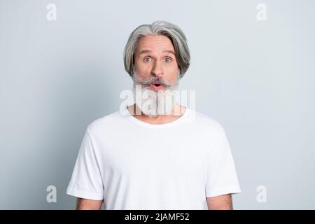 Photo d'un homme à la retraite branché impressionné porter un t-shirt blanc grands yeux longue barbe isolé couleur gris fond. Banque D'Images