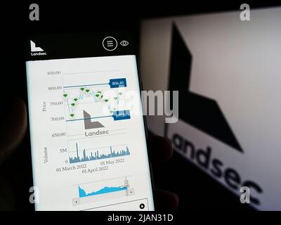 Personne tenant le logo de la page Web du téléphone portable de la société Land Securities Group plc (Landsec) à l'écran devant le logo. Concentrez-vous sur le centre de l'écran du téléphone. Banque D'Images