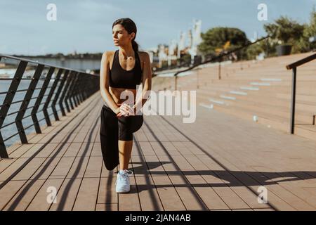 Jolie jeune femme de sport qui fait de l'exercice sur une promenade en bord de rivière Banque D'Images