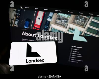 Personne détenant un smartphone avec le logo de la société Land Securities Group plc (Landsec) à l'écran devant le site Web. Mise au point sur l'affichage du téléphone. Banque D'Images