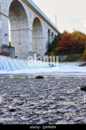 Petite chute d'eau dans la rivière Bobr sous le viaduc ferroviaire à Boleslaweic, en Pologne, le jour de l'automne. Banque D'Images