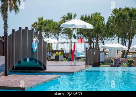 Piscine. Siège vide du maître-nageur avec chaise rouge sous un parasol blanc sur une tour près de la piscine Banque D'Images