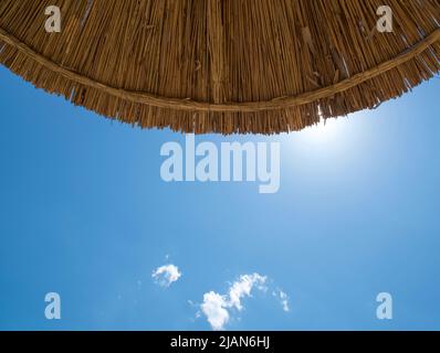 Parasol de plage contre le ciel bleu sur la plage. Vue de dessous, été Banque D'Images