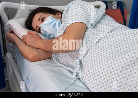 Une jeune femme hospitalisée portant un masque facial dans un lit de service hospitalier Banque D'Images