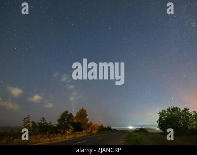 Comet Neowise C2020 F3 car il vole au-dessus dans le ciel d'été au-dessus de la prairie près de la route de campagne, région de Lviv, Ukraine. Banque D'Images