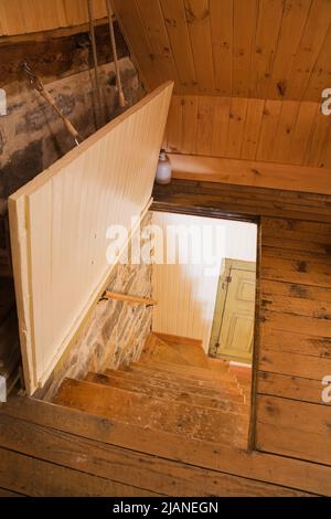 Porte ouverte et escalier en bois menant au rez-de-chaussée à l'intérieur de la vieille maison en pierre de style cottage Canadiana vers 1832. Banque D'Images