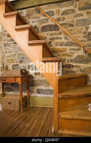 Escalier tournant menant à l'étage dans la cuisine à l'intérieur de la vieille maison en pierre de style cottage Canadiana vers 1832. Banque D'Images