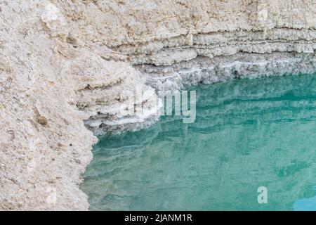 Gouffre rempli d'eau turquoise, près de la côte de la mer Morte. Feuilles de boue et de sel. Trou formé lorsque le sel souterrain est dissous par intrusion d'eau douce, en raison de la chute continue du niveau de la mer. Banque D'Images