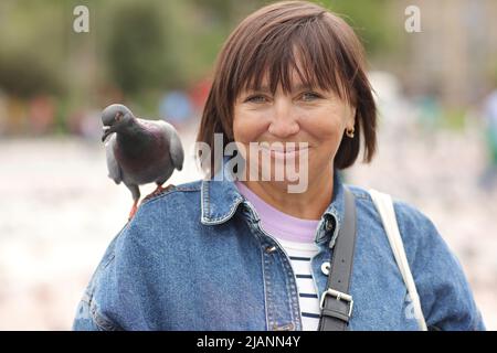 Femme souriante avec un pigeon sur son épaule. ravel autour de l'Europe. Banque D'Images